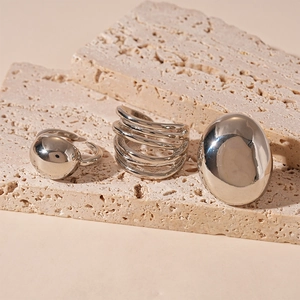 Macro detail of layered silver rings and smooth pebble-shaped ring on stone