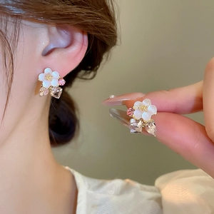 Detail view of flower stud earrings with white petals and pink crystal pendants