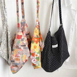 Selection of four floral and patterned canvas tote bags hanging in a minimalist setting