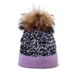Women's black sequin knit beanie with purple faux fur trim and large brown raccoon fur pom