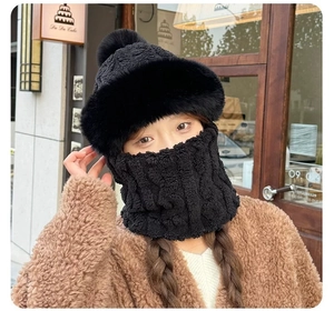 Detail of black winter knitted hood with faux fur collar and fluffy pom-pom decoration