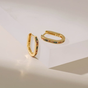 Elegant gold oval hoop earrings with sparkling rainbow cubic zirconia set on stone