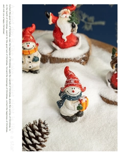 Close-up of resin Santa Claus and snowman figurines on simulated snow for Christmas decor
