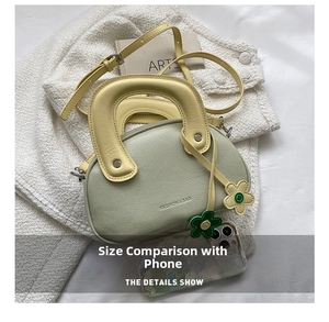 Détail du sac à main en cuir vert clair avec breloque fleur et poignée jaune