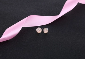 Macro view of S925 silver round stud earrings with shimmering pink crystal texture