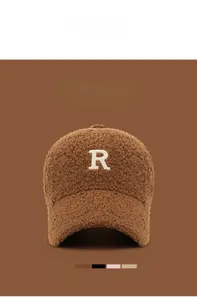 Detail of embroidered R letter on brown faux shearling baseball cap for winter