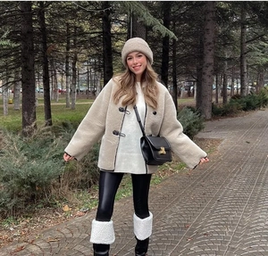Style de rue d'une veste en fausse fourrure beige avec pantalon en cuir noir et jambières