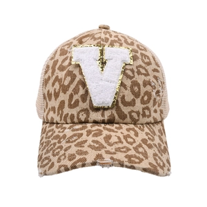 Dettaglio del cappellino leopardato con toppa V e rifiniture usurate sulla visiera
