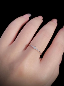 Detailed view of a slender 925 silver ring with zircons on a model's hand with black background