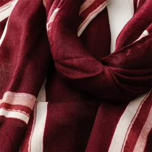 Detail of soft dark red scarf with beige stripes and linen-feel fabric texture