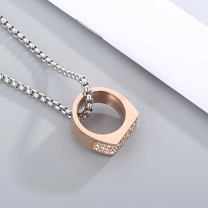 Detailed close-up of rose gold and cubic zirconia encrusted ring pendant on box chain