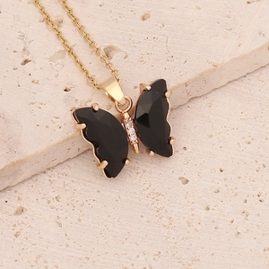Detailed close-up of golden butterfly pendant necklace with black gemstones and white zircon