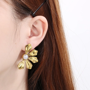 Macro shot of 18K gold-plated flower petal earring featuring a central pearl on a model