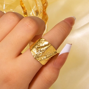 Gold wide textured stainless steel ring with hammered finish on model's finger