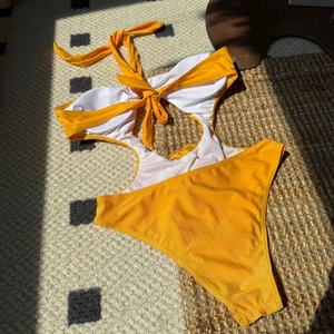Detail of contrast floral monokini with neck tie and waist cut-out in yellow and white