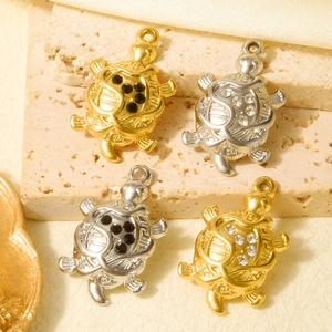 Detailed view of 18k gold and silver turtle pendants with sparkling zircons on stone