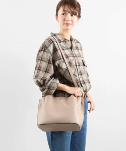 Model wearing a minimalist beige PU leather tote bag with elegant wavy edge details