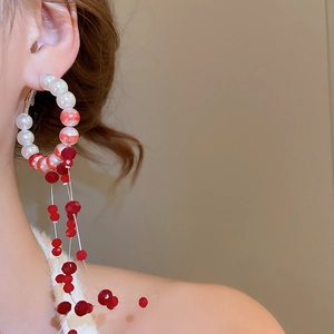 Macro shot of large red and white gradient beaded hoop earrings with long tassels