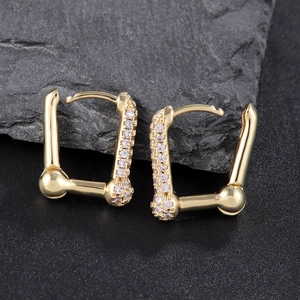 Elegant gold U-shaped hoop earrings with sparkling cubic zirconia on a dark stone