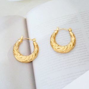 Detail of 18K gold plated hoop earrings with vintage vine texture on magazine background