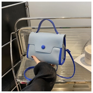 Detail of light blue textured mini bag with royal blue handles shown on handheld display