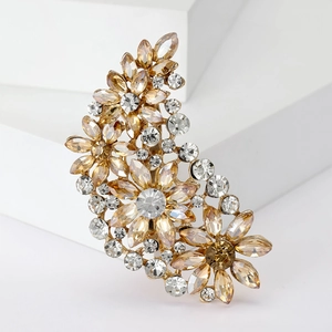 Close-up of golden floral brooch with sparkling champagne and clear crystals