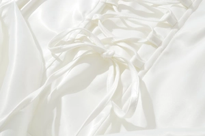 Détail de la robe en satin blanc avec laçage croisé élégant et texture de soie lisse