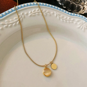 Detail of gold snake chain necklace featuring cat-eye stone and circular pendants