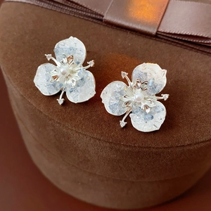 Detail of flower stud earrings with blue stone petals and white pearl on velvet box