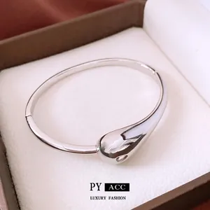 Polished gold plated teardrop bangle in a luxury brown jewelry gift box showcase