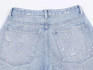 Gros plan sur un jean bleu clair orné de perles fantaisie et de strass brillants