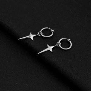Macro shot of silver stainless steel star earrings on a textured black surface