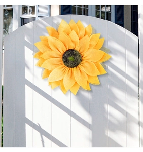 Macro view of large yellow mesh fabric sunflower wreath hanging on a white fence door