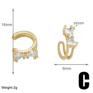 Detail view of gold-plated C-shaped ear cuff with zircon stones and twisted metal texture