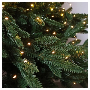 Close-up of warm white LED firefly lights wrapped around green Christmas tree branches