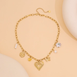 Gros plan d'un collier en acier doré avec des pendentifs cœur, fleur et papillon