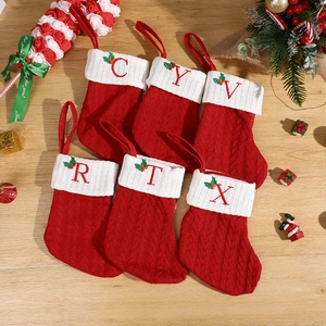 Set of 6 red knitted Christmas stockings with white cuffs and embroidered letters on wood