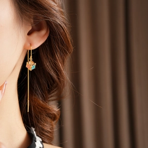 Close-up of elegant gold chain earrings with vibrant multicolor opal cube pendants