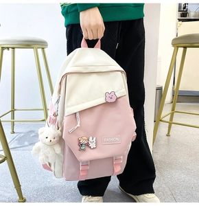 Detail eines rosa-beige geflickten Rucksacks mit niedlichen Tier-Badges und Plüschbär-Anhänger
