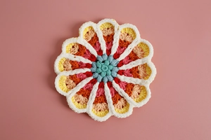 Macro shot of colorful handmade crochet floral coaster with detailed knit texture