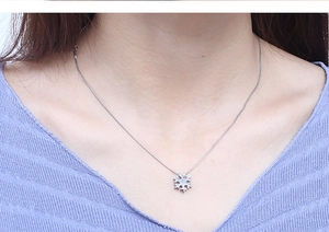 Close-up of a silver snowflake pendant necklace worn on a blue knit sweater