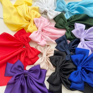 Detail showing oversized satin bow hair clips in multiple vibrant colors on white background