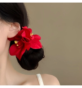 Detalle de cerca de un clip de pelo de orquídea roja vibrante usado en un moño clásico.