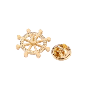 Detailansicht einer goldenen Steuerrad-Brosche mit klassischem Schmetterlingsverschluss