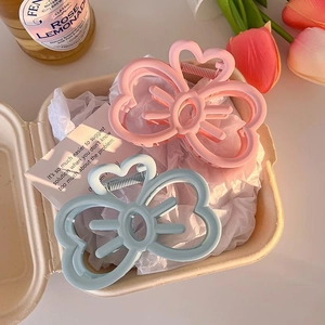 Detailed view of matte heart and bow hair claws in pink and blue colors on tissue paper