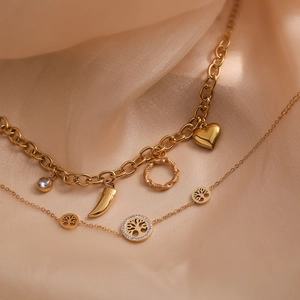 Gold tree of life and heart pendant chain bracelets on elegant champagne silk background