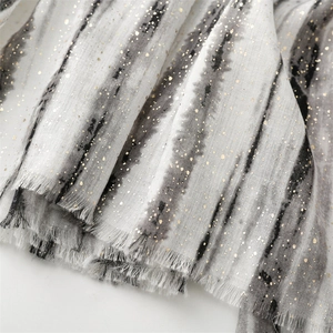 Close-up of gold foil bamboo print on grey gradient linen-feel scarf with fringe edges
