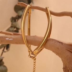 Detailed close-up of a 18K gold-plated bamboo link necklace on a rustic wood branch