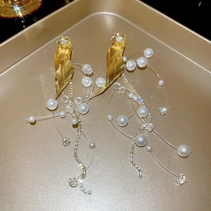Detailed shot of luxury gold flower leaf earrings with sparkling zircon and pearl tassels