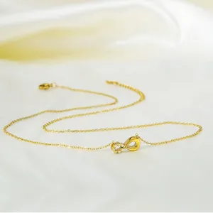 Minimalist gold infinity necklace with pavé zircon stones on white silk background